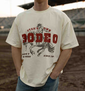 Person wearing a t-shirt with a rodeo graphic and text in an outdoor setting
